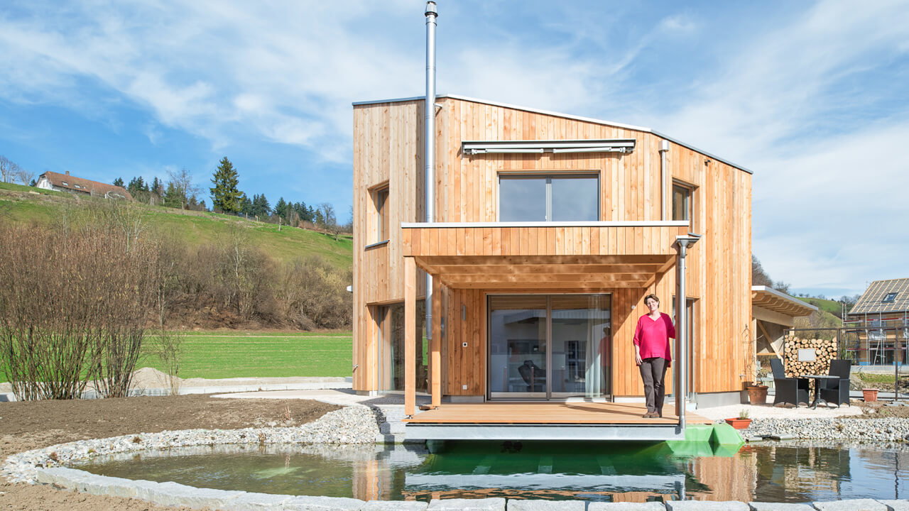 Ein Tiny House auf einer Wiese mit Terrasse und Teich