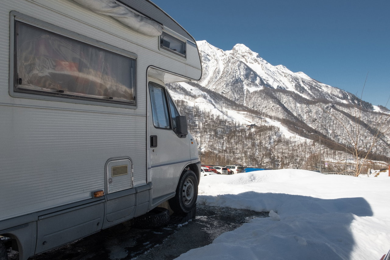 Ein Wohnmobil steht im Schnee vor Bergen.