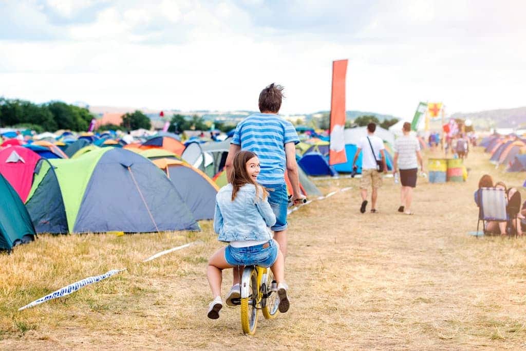 Junge Menschen fahren mit einem Fahrrad über ein Festivalgelände @depositphotos