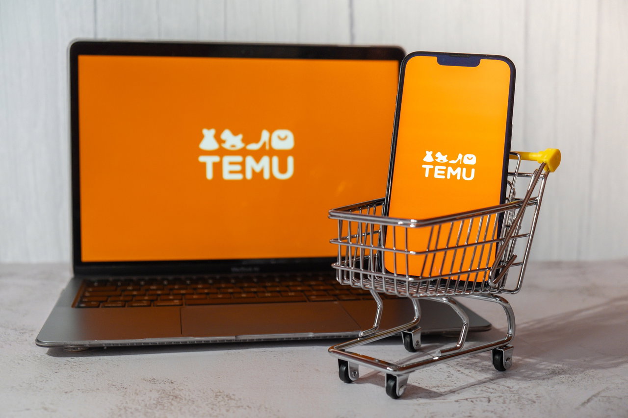Temu Online-Shop auf Laptop und Handy, Handy ist in einem Mini-Einkaufswagen