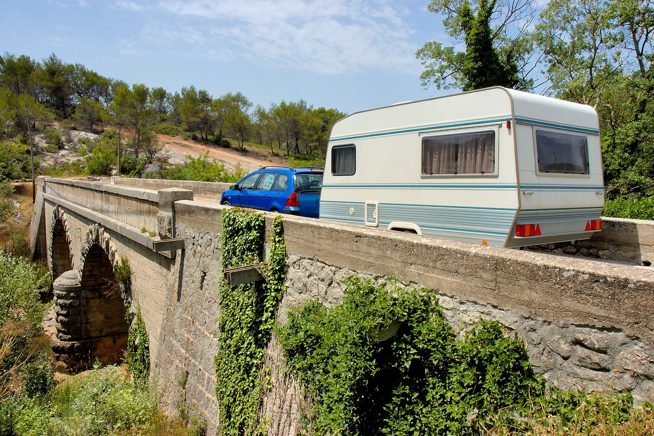 Gespann aus Wohnwagen und Zugfahrzeug (Pkw) auf einer Brücke