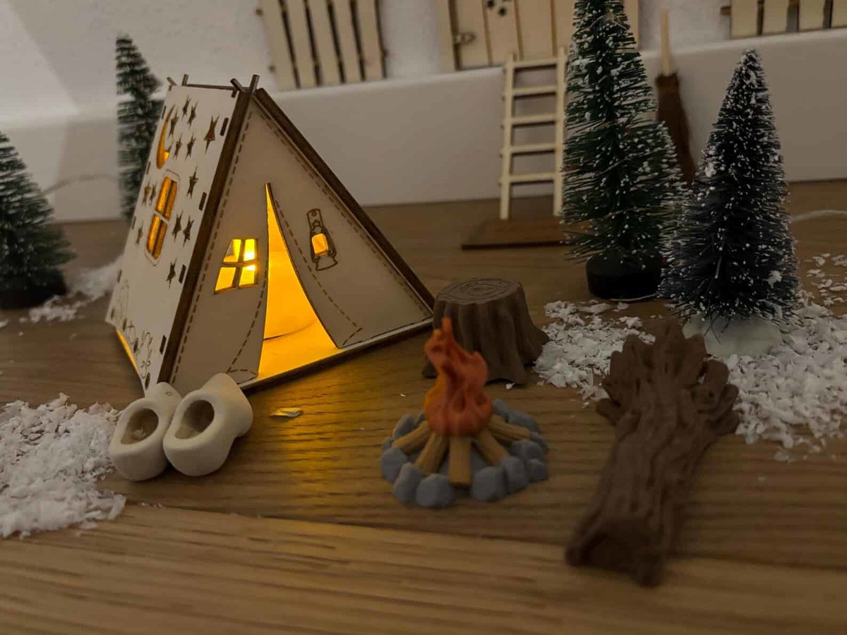 Stimmungsvolle Camping-Deko mit kleinen Bäumen, Feuerstelle & Naturmaterialien, perfekt für Camperstyle.